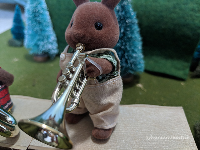 Sylvanian Families Herb Wildwood plays the trumpet. An orthodontic rubber band holds the instrument on his hand